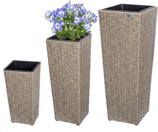 Drie crème kleurige, vierkante bloempotten van polyrattan met rotanlook. Eén bloempot met blauwe bloemen.