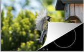 KitchenYeah® Inductie beschermer 80x52 cm - Een koolmees vliegt een vogelhuisje in - Kookplaataccessoires - Afdekplaat voor kookplaat - Inductiebeschermer - Inductiemat - Inductieplaat mat