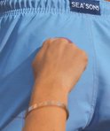 Blauwe zwembroek met label 'SEA'S SONS', hand op de broek gedrukt.