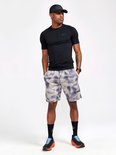 Man in zwart Craft shirt met korte mouwen en grijze shorts met tie-dye patroon. Draagt zwarte pet en sportschoenen.