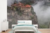 Behang - Fotobehang De Meteora kloosters tussen de wolken - Breedte 600 cm x hoogte 400 cm