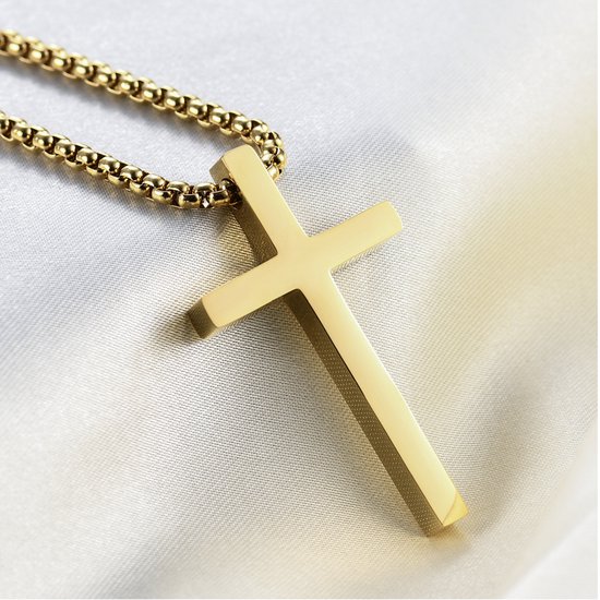 Gouden kruisketting met dikke schakel, close-up op glanzend crèmekleurig satijn.