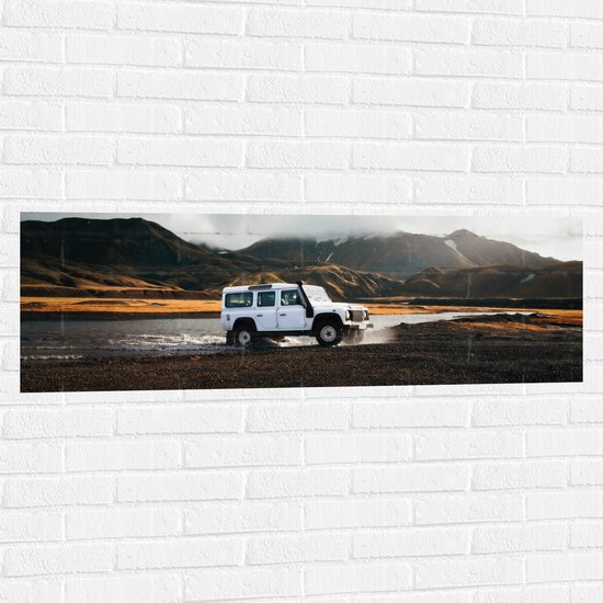 WallClassics - Muursticker - Witte Grote Auto door het Water bij het Berglandschap - 120x40 cm Foto op Muursticker