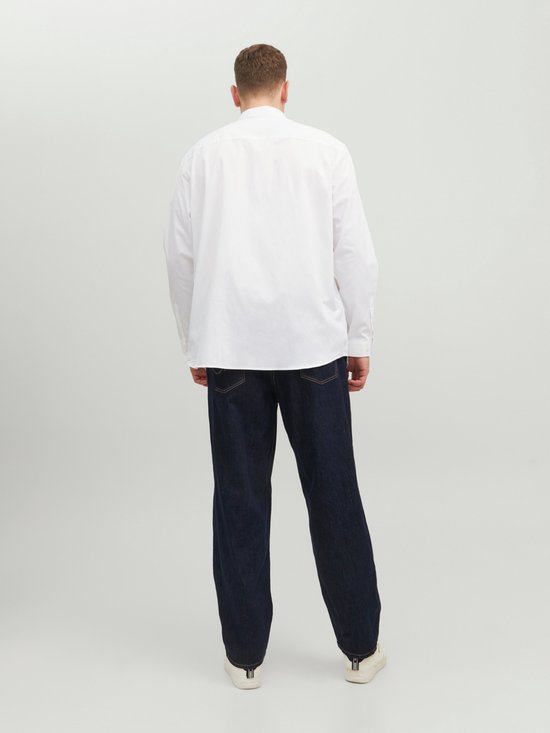 Man van achteren gezien, draagt een wit Jack & Jones overhemd en donkere jeans.