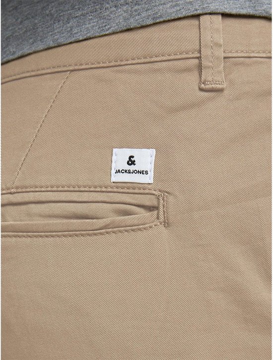 Detail van de achterzak van een beige chino broek met "Jack & Jones" label.