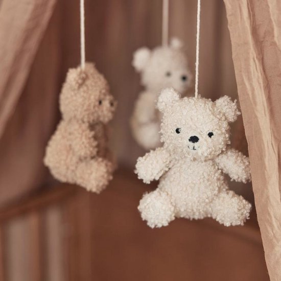 Close-up van drie teddyberen mobiel, met focus op de lichtbeige beer vooraan.