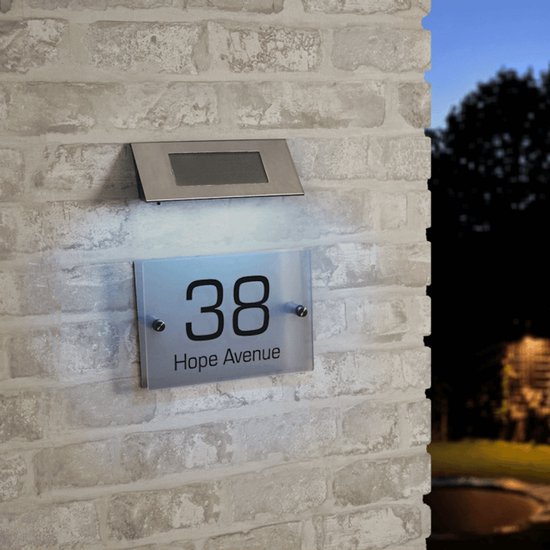 Verlicht huisnummer 38 'Hope Avenue' op een witte bakstenen muur, met zilveren zonne-armatuur bovenaan.