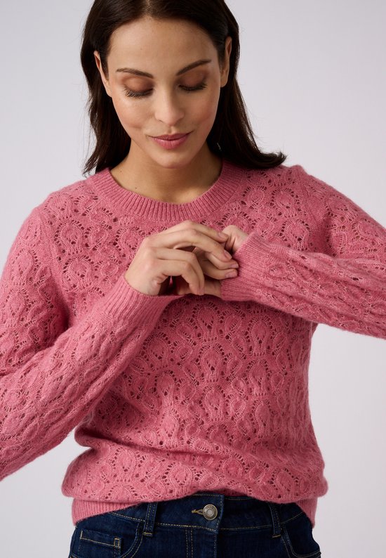 Model draagt een roze Damart trui met opengewerkte patronen, lange mouwen en een ronde hals.