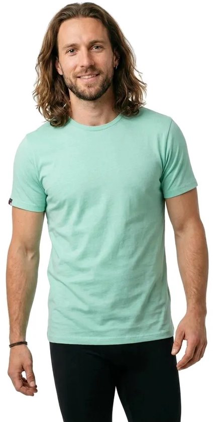 Homme aux longs cheveux bruns portant un t-shirt vert d'eau à manches courtes.