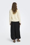 Model van achteren met crèmekleurige, pluizige trui, wijde zwarte broek en bruine hakken.