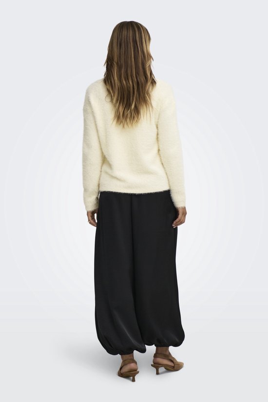 Model van achteren met crèmekleurige, pluizige trui, wijde zwarte broek en bruine hakken.