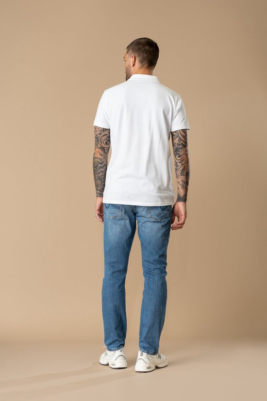 Achterkant van man in witte polo en blauwe rechte jeans.