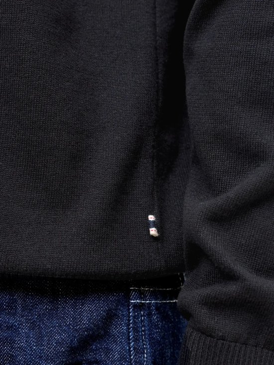 Detail van de onderkant van een zwart Jack & Jones poloshirt met logo strepen.
