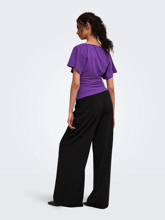 Model op de rug gezien in een paarse ONLY top met gedrapeerde halslijn en zwarte wijde broek.