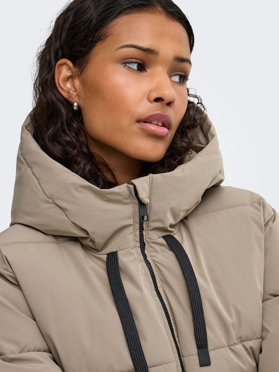 Close-up van een beige pufferjas met capuchon en zwarte trekkoorden bij de kraag.