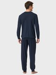 Achteraanzicht van het model in een donkerblauwe pyjamaset met verticaal gestreept bovenstuk en effen broek.