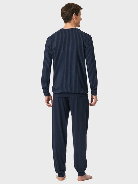 Achteraanzicht van het model in een donkerblauwe pyjamaset met verticaal gestreept bovenstuk en effen broek.