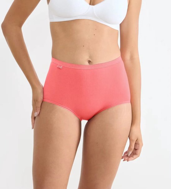 Model draagt een koraalkleurige maxi-slip met hoge taille en Sloggi-label.