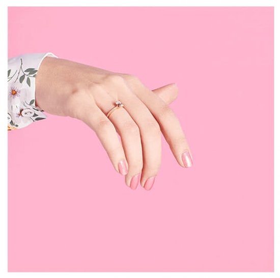 Hand met ring op de ringvinger en nagels gelakt met parelmoerachtige, lichtroze nagellak.