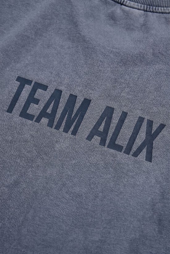 Blauwe sweater met de tekst 'TEAM ALIX' in grote letters op de rug.