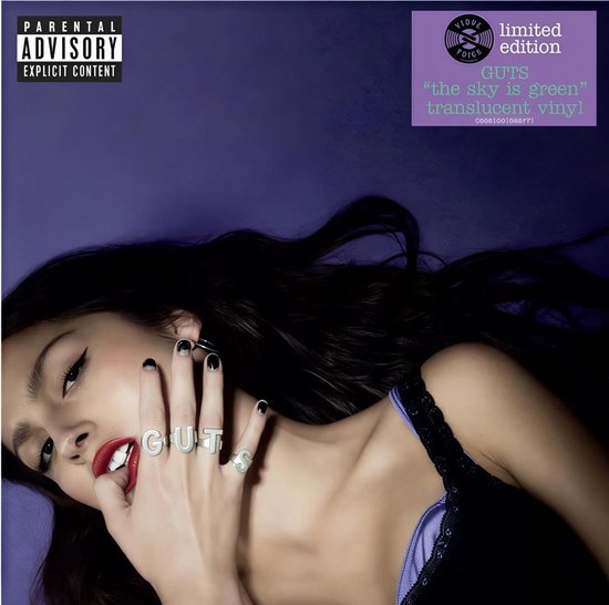 Olivia Rodrigo met zwarte nagels en 'GUTS' ringen, tegen een paarse achtergrond met 'Limited Edition' sticker.