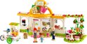 LEGO Friends café set met drie miniatuurfiguren, een foodtruck en groen versierde uitbreidingen. Het café is wit met een oranje dak.