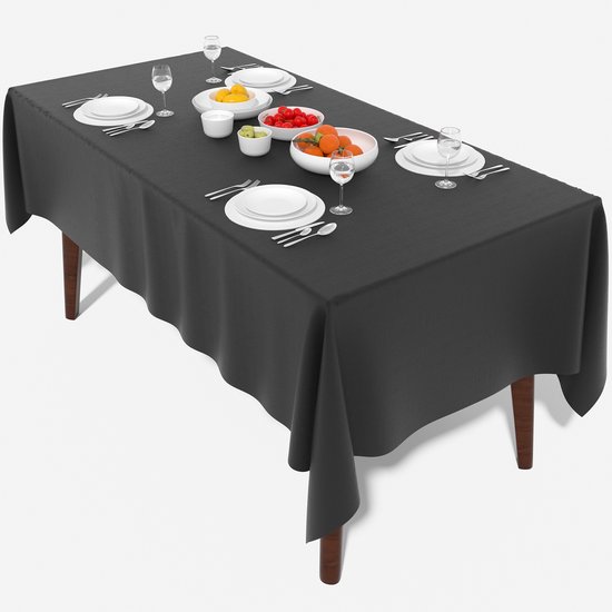 Een langwerpig zwart tafelkleed met een gedekte tafel met servies en fruit, op een witte achtergrond.