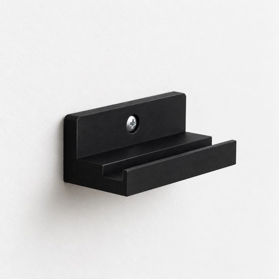 Zwarte vinyl wandhouder gemonteerd op een witte muur, met een centrale schroef voor bevestiging.