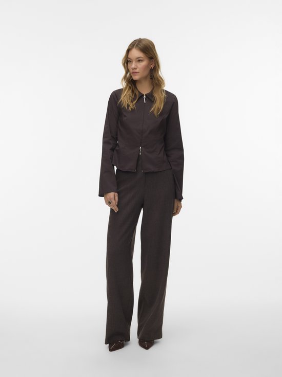 Model in een donkerbruine pantalon met wijde pijpen en een bijpassend jasje.