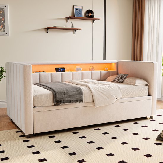 Crèmekleurig gestoffeerd ledikant met gestreepte rugleuning, uittrekbaar bed, ingebouwde opbergruimte en sfeervolle led-verlichting.