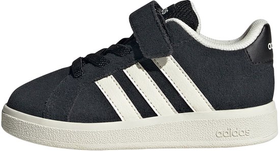 Zij-aanzicht van zwarte Adidas sneakers met witte strepen, klittenband en crèmekleurige zool.