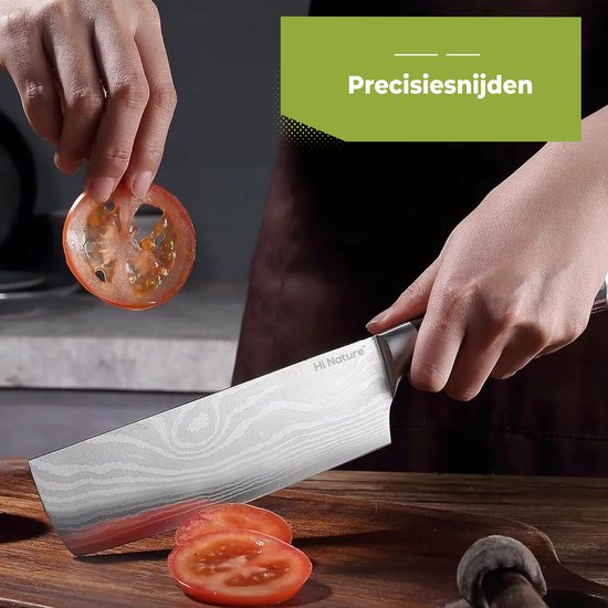 Een hand snijdt een tomaat in plakjes met een Hi Nature nakiri mes met damastpatroon en zwart handvat.