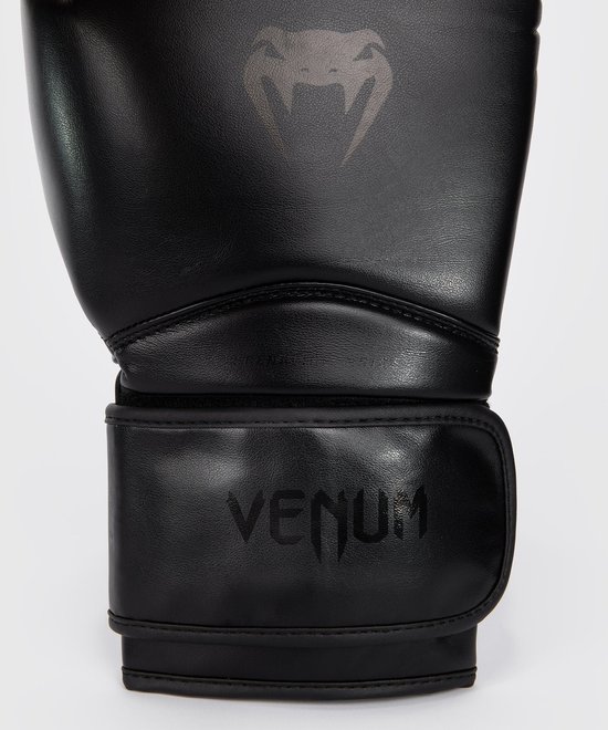Close-up van een zwarte VENUM bokshandschoen met opgedrukt logo en polsband.