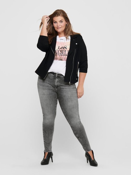 Model met bruin haar in een zwarte jas, T-shirt met tekst en grijze skinny jeans.