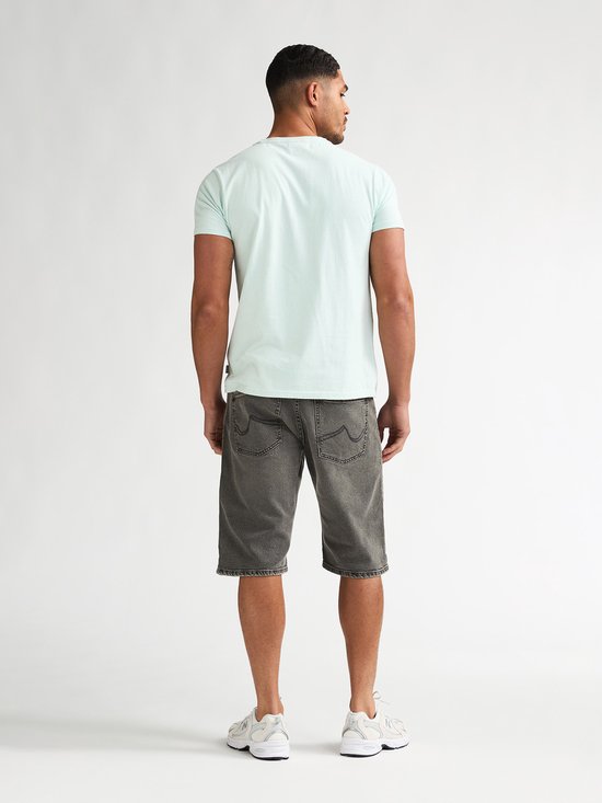 Man in lichtgroen T-shirt en grijze spijkerbroekshorts, rug zichtbaar.