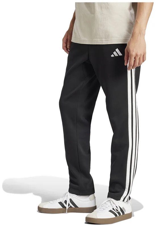 Man draagt zwarte trainingsbroek met witte strepen op de zijkanten en een wit Adidas logo.