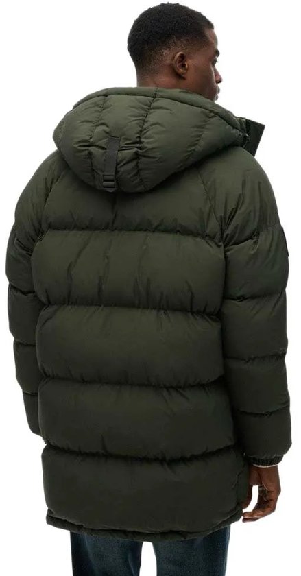 Een man, van achteren gezien, draagt een lange, donkergroene, gewatteerde parka met capuchon.