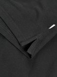 Detail van de split in de zoom van een zwarte poloshirt met korte mouwen.