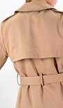 Achterkant van een camelkleurige lange trenchcoat met ceintuur.