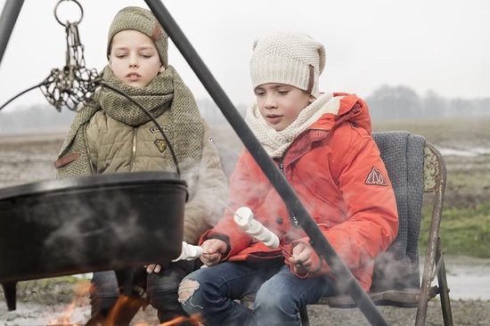 Twee jongens die marshmallows roosteren boven een vuur. Een jongen draagt een oranje jas, de ander een groene jas.