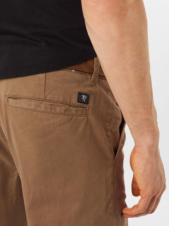 Close-up van het achterzakdetail van een bruine chino broek met logo.