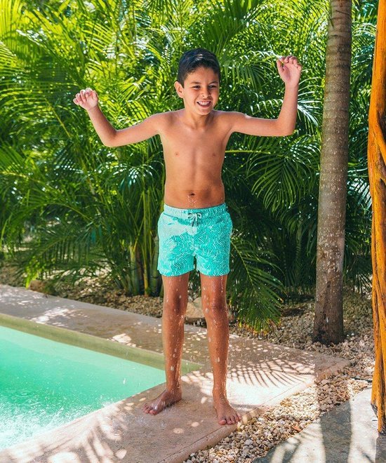 Jongen in turquoise zwembroek met wit patroon, springend bij een zwembad.