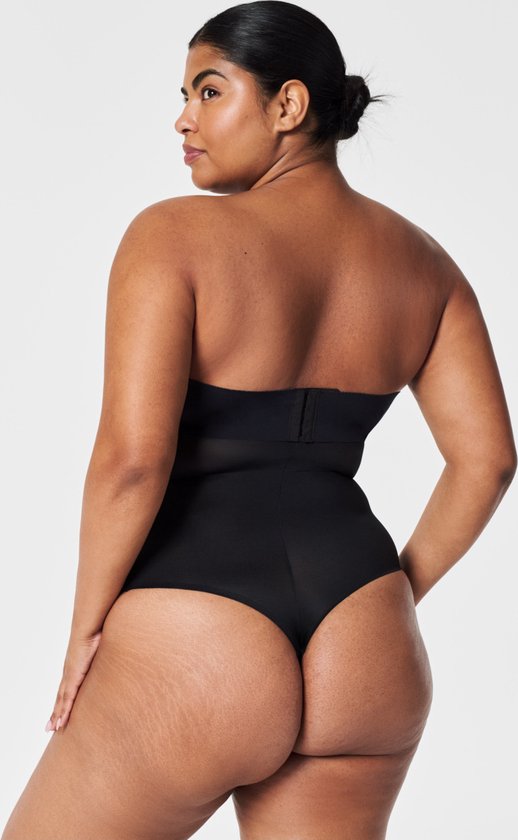 Modèle vu de dos, portant un body noir bandeau taille haute avec fermeture tanga. La ceinture est visible.