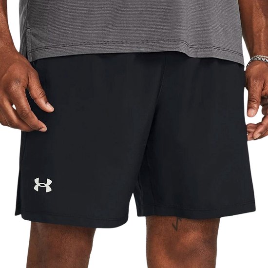 Man draagt een zwarte Under Armour sportbroek van 7 inch met een wit logo op de linkerpijp.