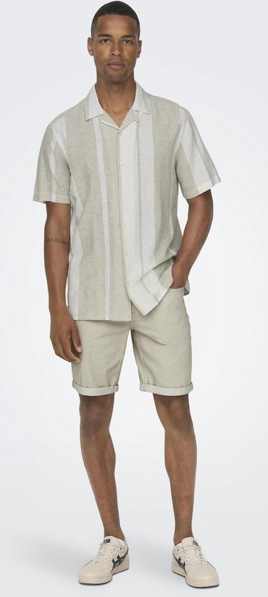 Man in licht groen hemd met verticale strepen, beige shorts.