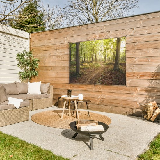 Decoratieve poster van een bos met pad, opgehangen aan een houten muur, bij een loungeset.