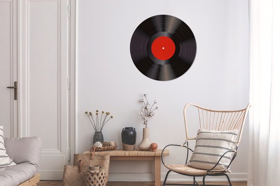 Zwarte vinyl LP met rood middellabel, hangend aan een muur in een woonkamer.
