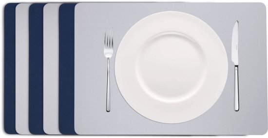 Trois sets de table bleu foncé et trois gris empilés. Une assiette avec des couverts repose sur le set gris avant.