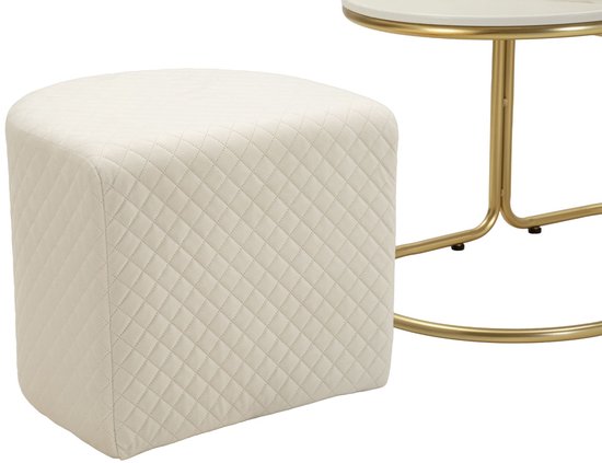 Crèmekleurige, gewatteerde poef met vierkante zitting en afgeronde hoeken, naast een gouden tafel.