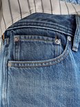 Detail van de zakken van een lichtblauwe spijkerbroek met klinknagels en stiksels.
